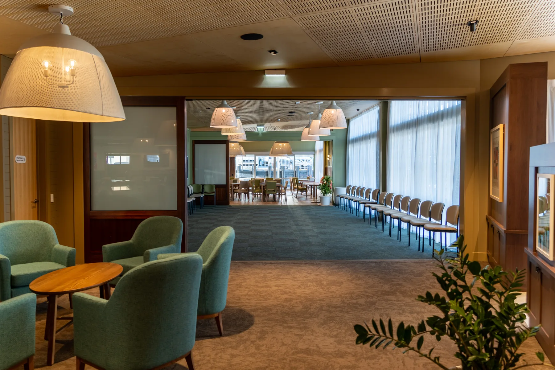 A room laid out for an event, with rows of chairs facing through to the dining area beyond