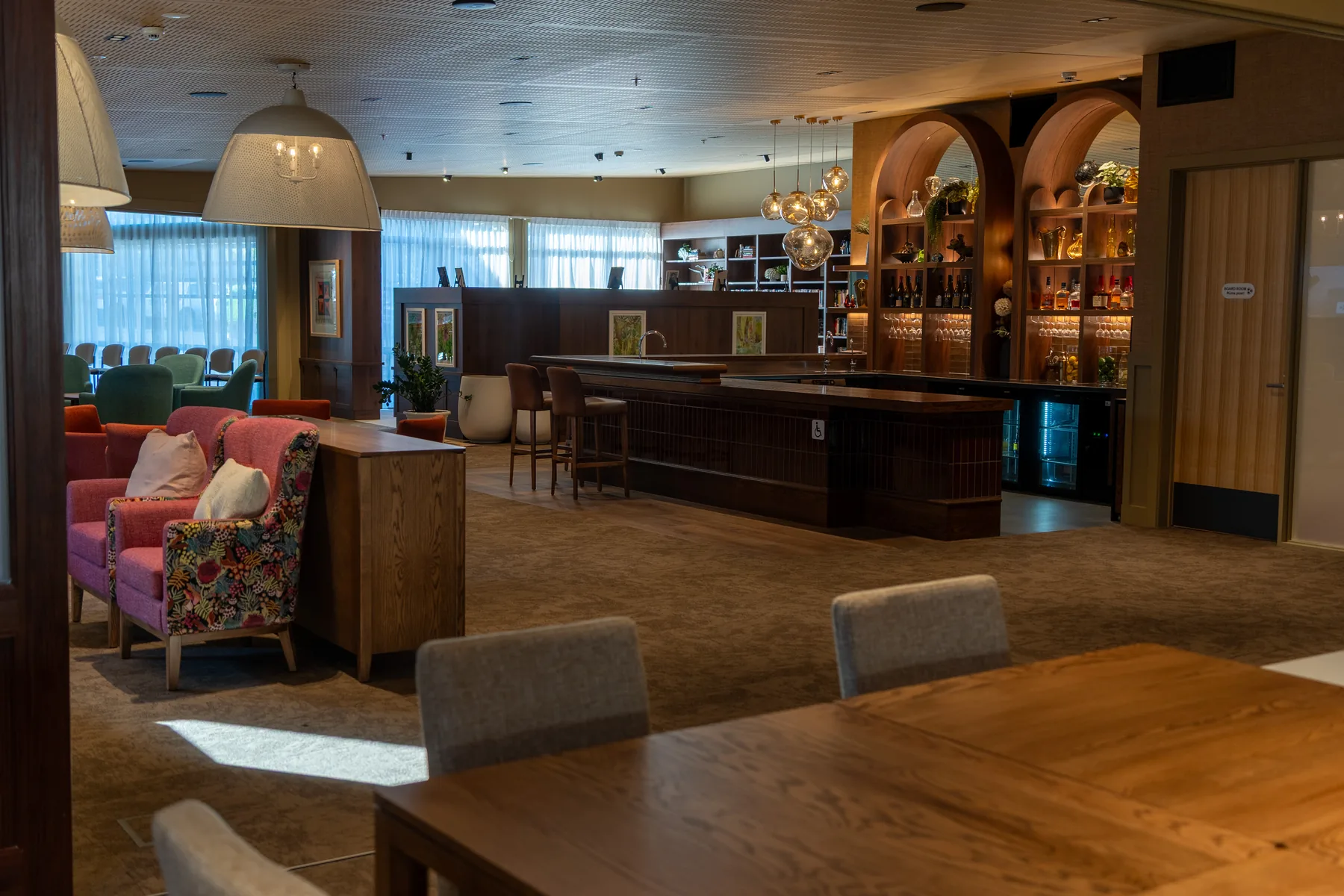 A quieter corner of the lounge, with patterned armchairs by the windows and a long table for shared meals
