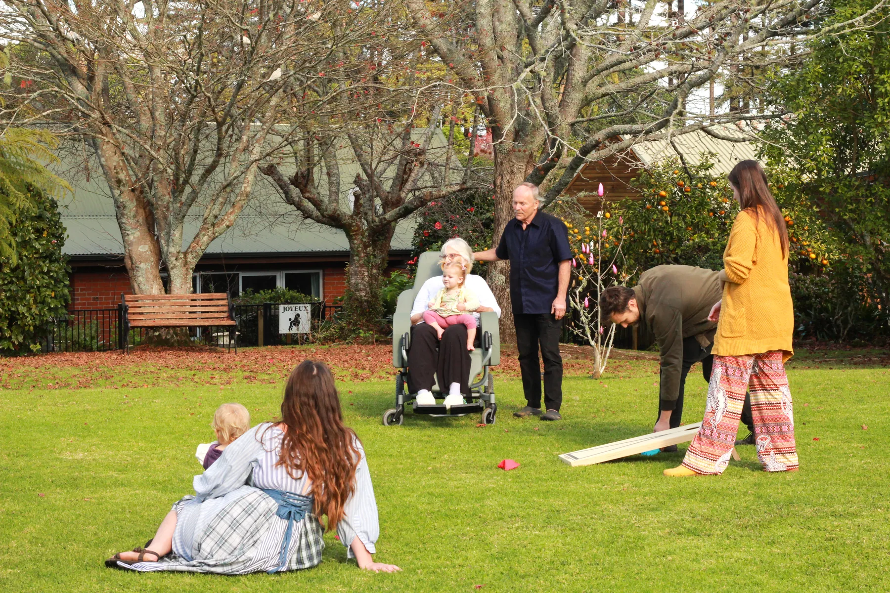 Adults and children gather around a beanbag game on the village lawn