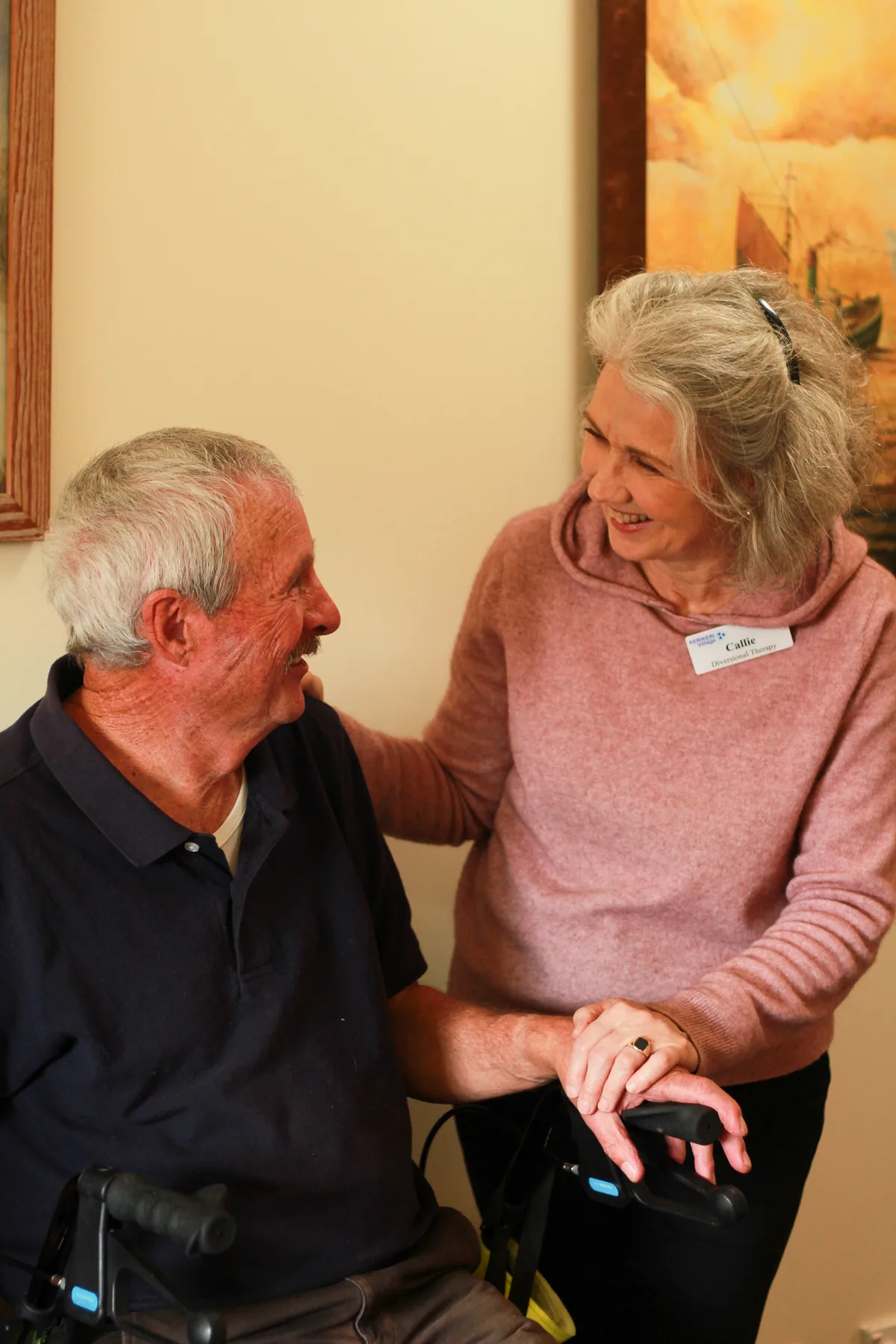A member of the care team walking beside a resident using his walking frame