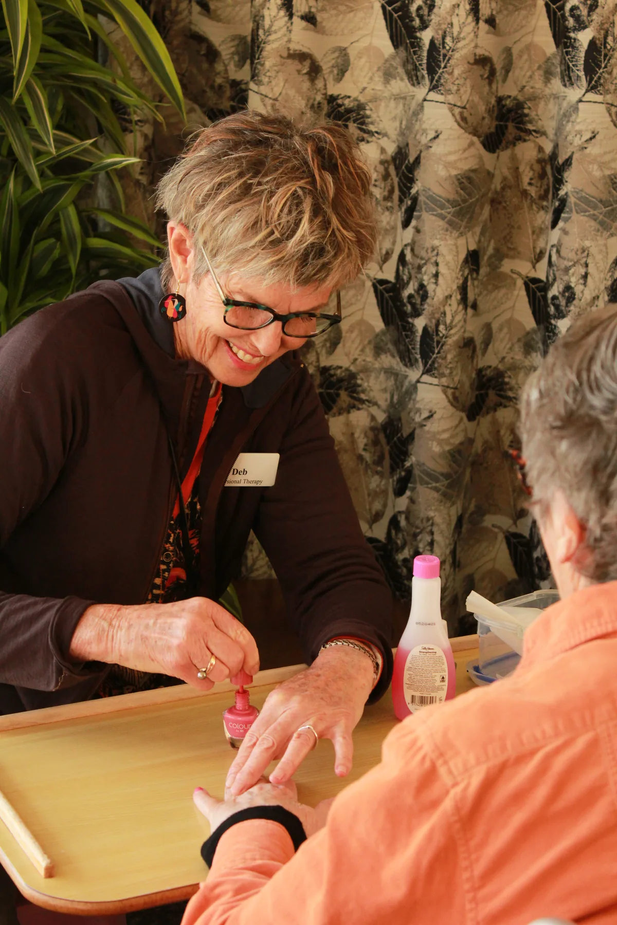 A staff member painting a resident's nails during an activity session