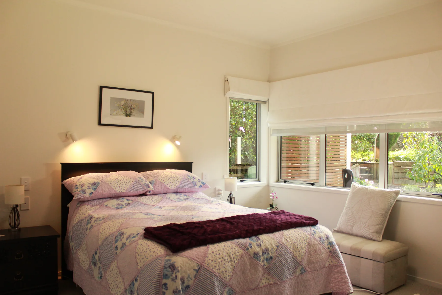 A cottage bedroom with a double bed and a wide window over the garden