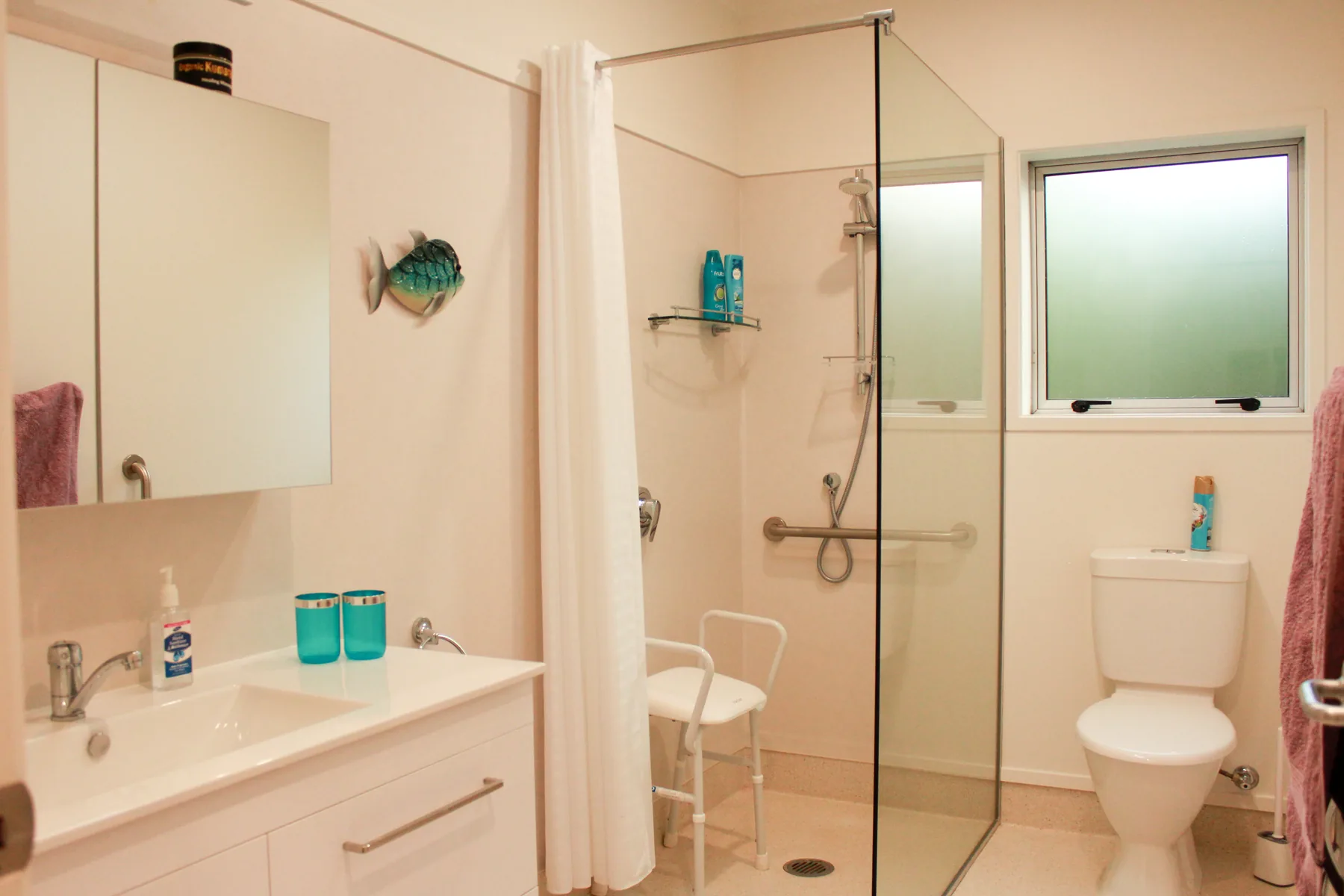 A cottage bathroom with a step-in shower, grab rail and vanity