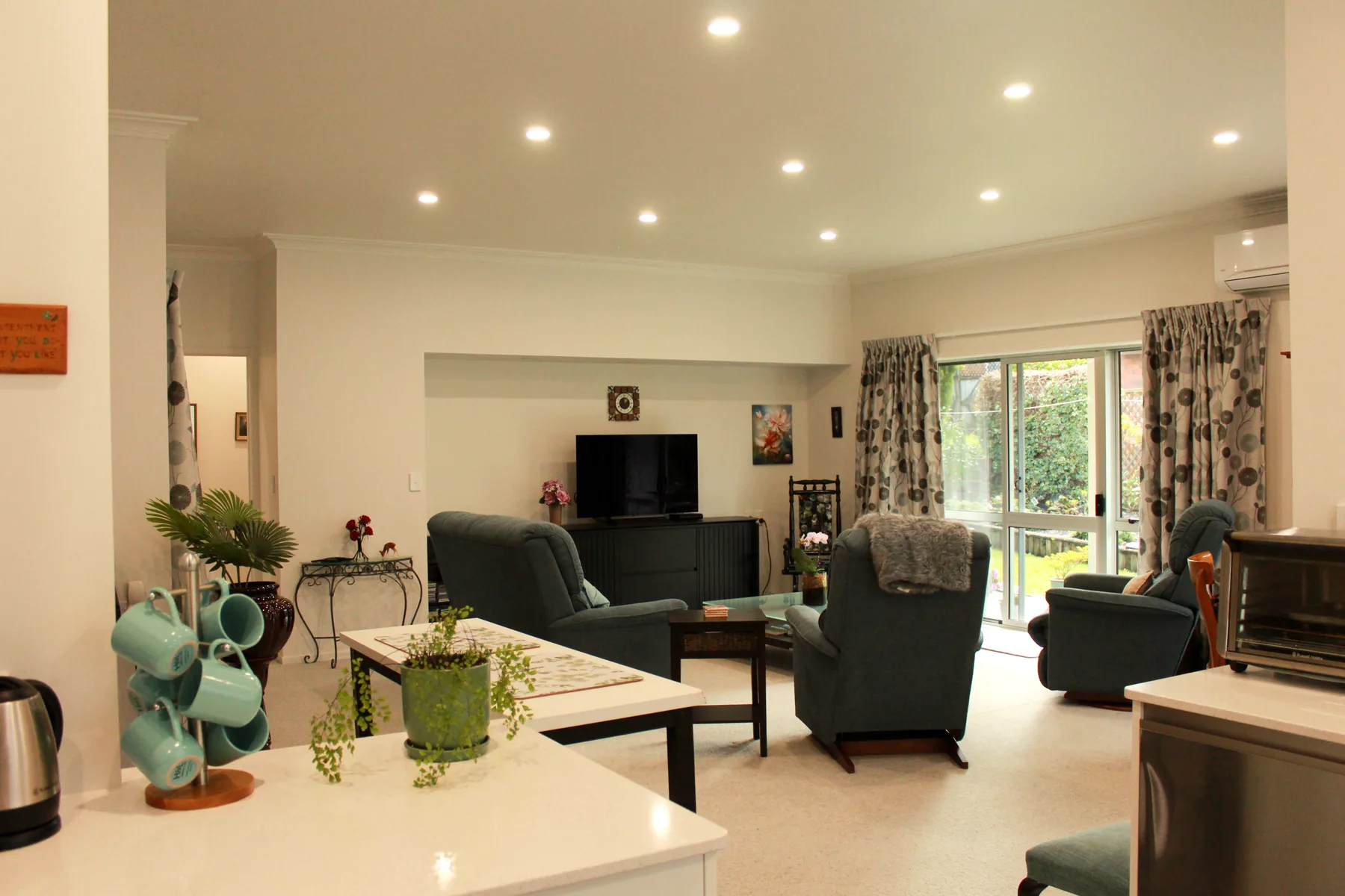 An open-plan cottage living area leading through to the kitchen, with sliding doors to the patio