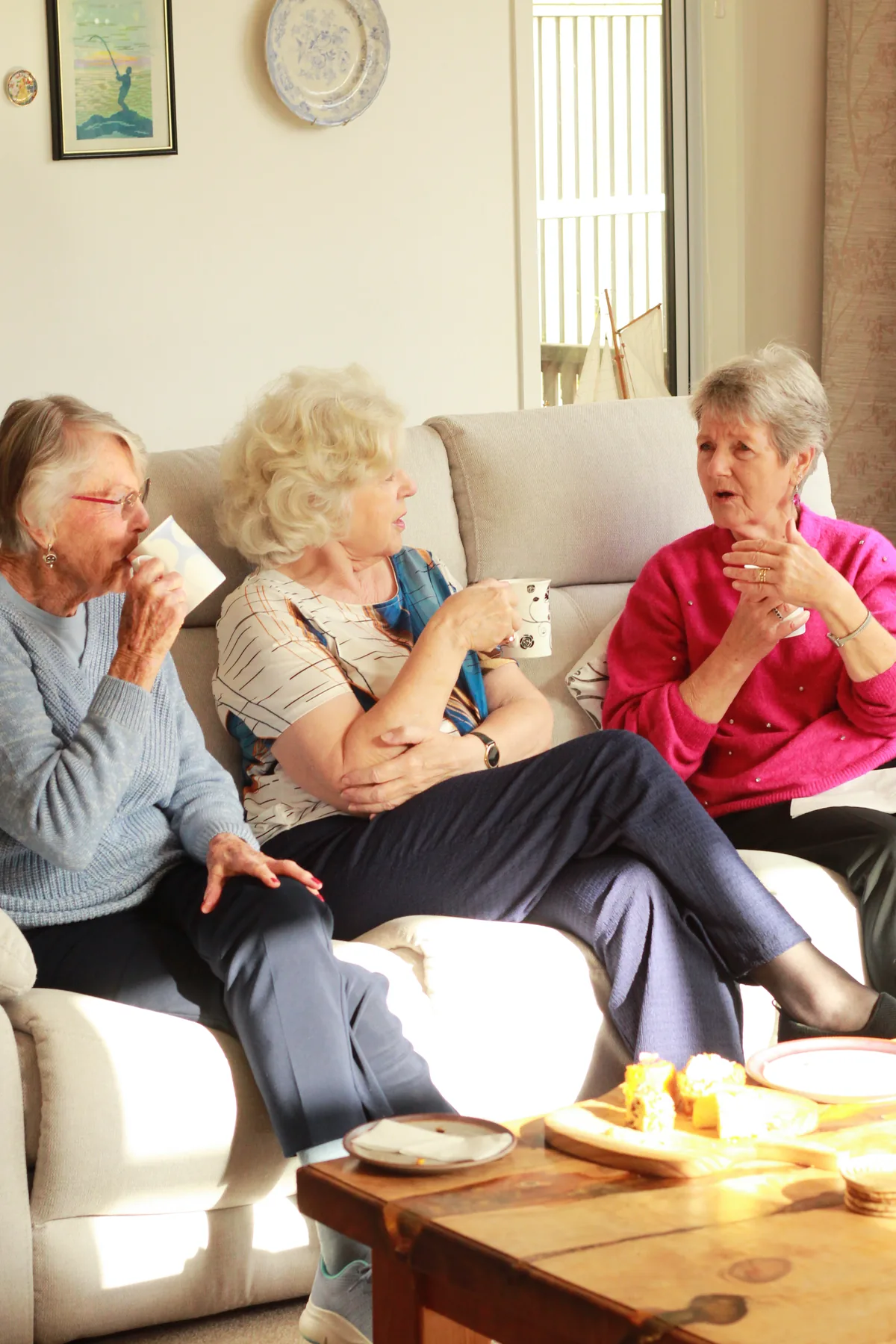 Three residents chatting over afternoon tea in a sunny lounge